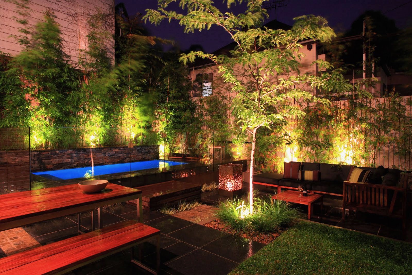 Completed garden lighting illuminating trees and seating at night
